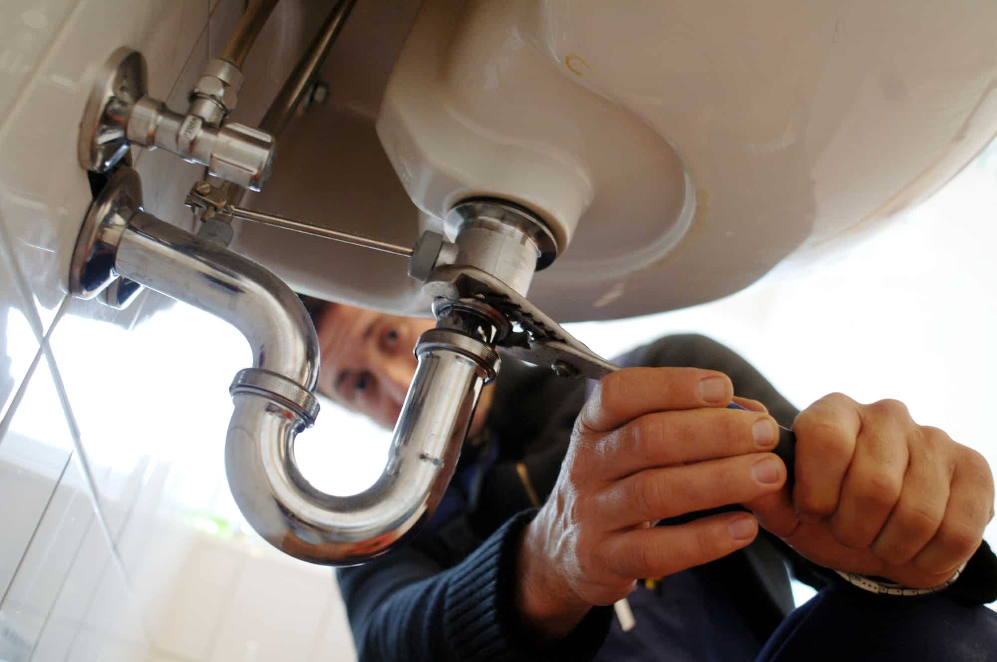 Close-up of plumber fixing sink with work tool in bathroom